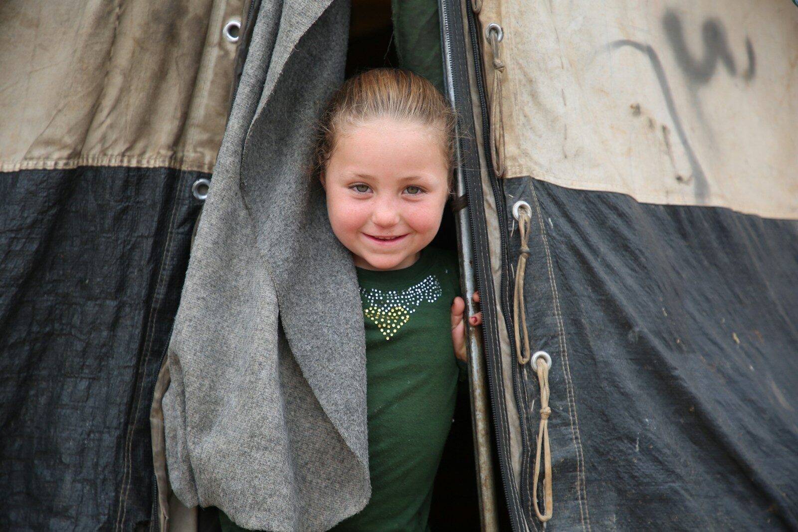 A young girl standing inside of a black and white tent